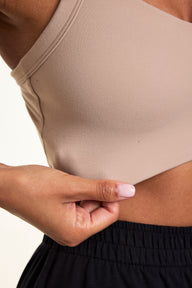 Close-up on a light studio backdrop of Courtney wearing the Whipped Knit V-Neck Bralette in Mushroom with black lounge pants. The bralette features a soft V-neckline, wide straps, and smooth knit fabric. 