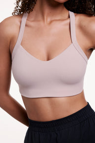 In a close-up studio shot, Courtney wears the Whipped Knit V-Neck Bralette in Mushroom, highlighting the V-neckline, smooth knit fabric, and wide straps designed for comfortable support.