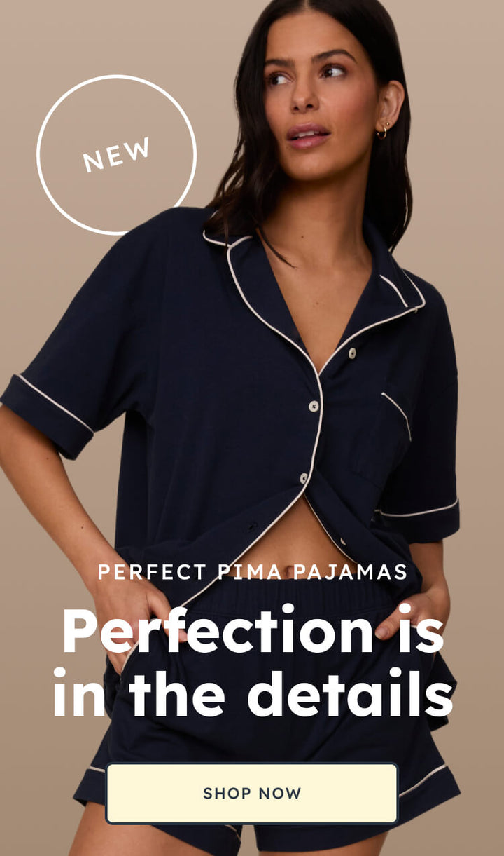 Homepage banner with two models in navy and olive Piped Pima Pajama Sets. Text reads "Perfect Pima Pajamas" and "Perfection is in the details," with a "Shop Now" button. A "New" badge is positioned near the top.