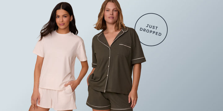 Two models pose against a light blue background — one wearing the Cloud Cotton T-shirt and shorts set, and the other in the olive Piped Pima Pajama Set. A circular badge reads "Just Dropped."