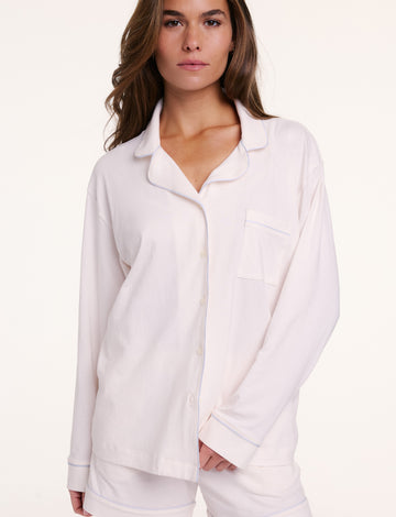 On a neutral backdrop, Gianna wears the Perfect Pima Pajama Long Sleeve Shirt in Ivory with matching shorts. The shirt is buttoned and features a relaxed fit, long sleeves, and a chest pocket.