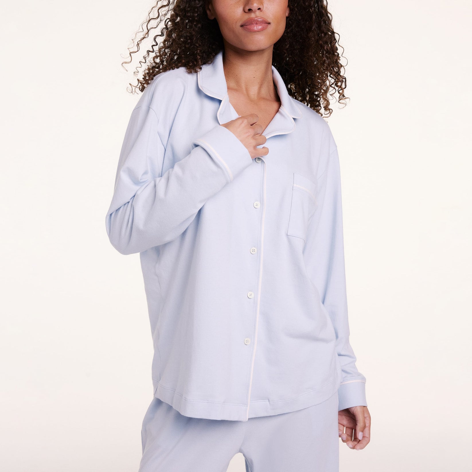 In a studio setting, Courtney wears the Perfect Pima Pajama Long Sleeve Shirt in Soft Blue, shown in a close-up highlighting the button-front detail and chest pocket.