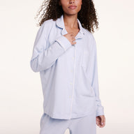 In a studio setting, Courtney wears the Perfect Pima Pajama Long Sleeve Shirt in Soft Blue, shown in a close-up highlighting the button-front detail and chest pocket.