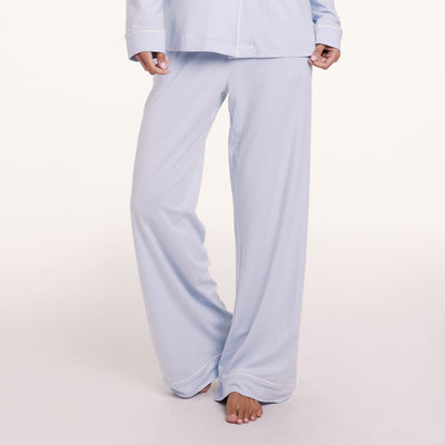 On a light studio backdrop, Courtney wears the Perfect Pima Pajama Pants in Soft Blue, featuring a wide-leg fit and smooth, lightweight fabric.