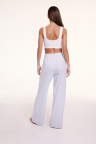 On a light studio backdrop, Linni wears the Perfect Pima Pajama Pants in Soft Blue, shown from the back with a relaxed, wide-leg silhouette.