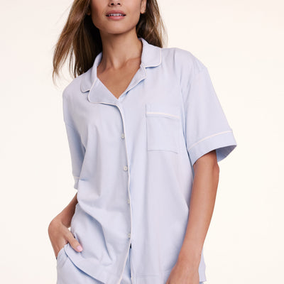 In a studio setting, Linni wears the Perfect Pima Pajama Short Sleeve Shirt in Soft Blue, shown in a close-up highlighting the button-front detail, collar, and chest pocket.