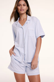 In a studio setting, Linni wears the Perfect Pima Pajama Shorts in Soft Blue with a matching short sleeve shirt, featuring a relaxed fit and lightweight, breathable fabric.