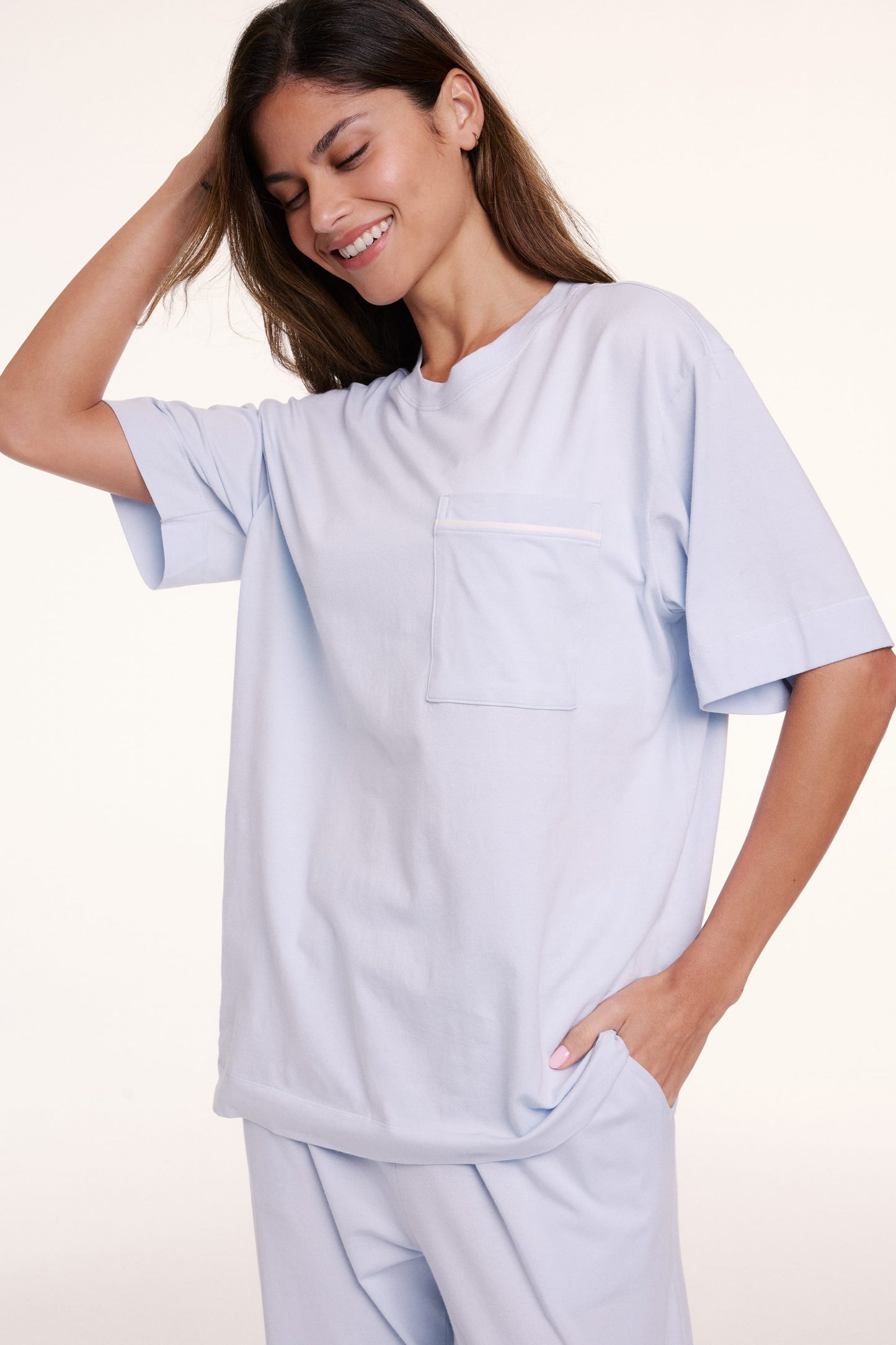 In a studio setting, Linni wears the Perfect Pima Pajama Tee in Soft Blue, shown in a relaxed fit with a crew neckline, short sleeves, and a chest pocket. sizing: Linni wears size Small