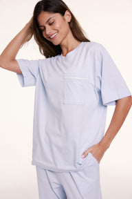 In a studio setting, Linni wears the Perfect Pima Pajama Tee in Soft Blue, shown in a relaxed fit with a crew neckline, short sleeves, and a chest pocket. sizing: Linni wears size Small