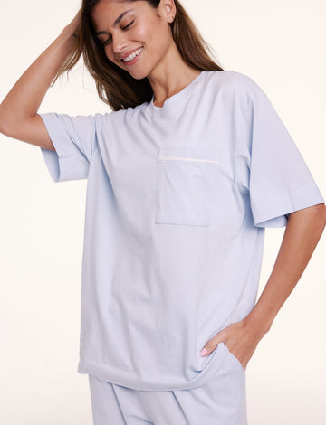 In a studio setting, Linni wears the Perfect Pima Pajama Tee in Soft Blue, shown in a relaxed fit with a crew neckline, short sleeves, and a chest pocket. sizing: Linni wears size Small