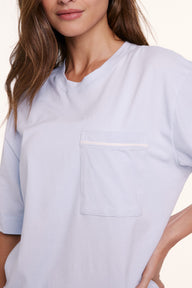 In a studio setting, Linni wears the Perfect Pima Pajama Tee in Soft Blue, shown in a close-up of the chest pocket and smooth, breathable fabric.