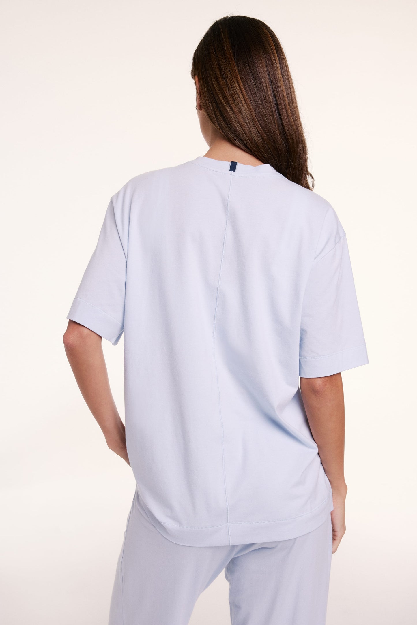 In a studio setting, Linni wears the Perfect Pima Pajama Tee in Soft Blue, shown from the back with a relaxed fit and short sleeves.