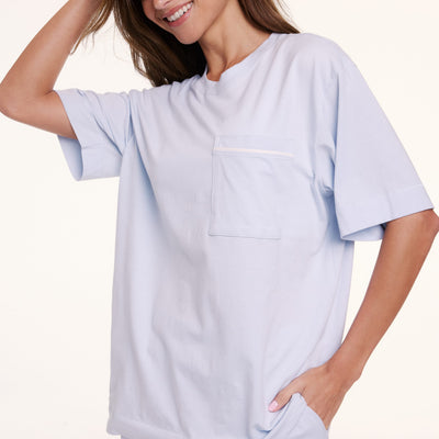 In a studio setting, Linni wears the Perfect Pima Pajama Tee in Soft Blue, shown in a close-up highlighting the soft fabric and chest pocket detail.