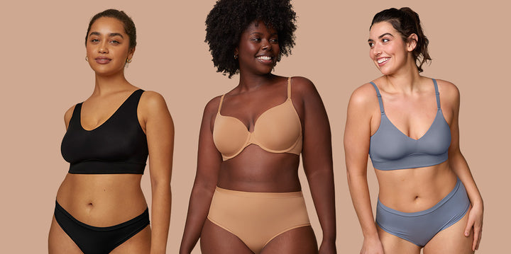 Akesha poses with two other models while wearing the T Shirt Base Bra and Bliss Highwaist Brief in Tan. The model on the right looks at Akesha, wearing the Bliss Triangle Bralette and Highwaist Briefs in Slate. The model on the left wears the Bliss and Bliss Bikini in Black while looking at the camera. The comfortable and supportive fit are highlighted for all products. 