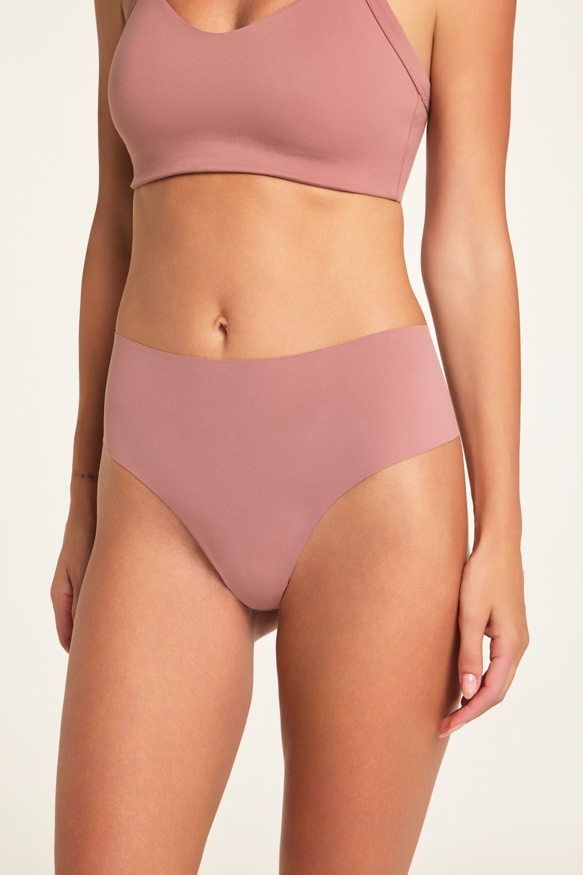 On a light studio backdrop, Holly wears the Whipped Knit V-Neck and No-Show Highwaist Thong in Plum, shown from the front.
