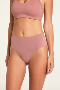 On a light studio backdrop, Holly wears the Whipped Knit V-Neck and No-Show Highwaist Thong in Plum, shown from the front.