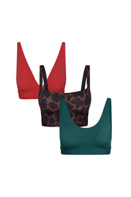 Flat lay of the Blissmas Gift Bundle featuring three bralettes in Cherry Red, Leopard Print, and Teal, shown in a ghost lay arrangement.