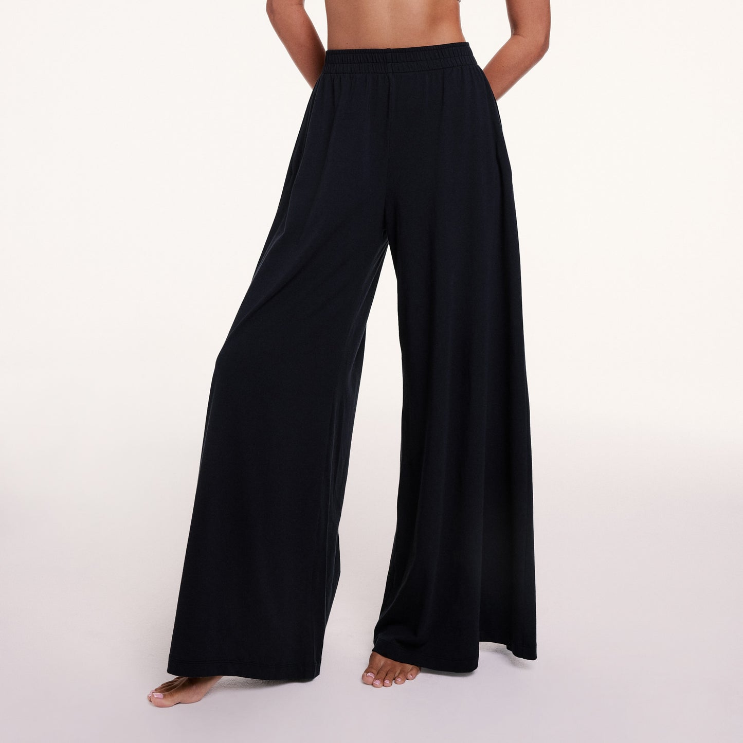 In a studio setting, Courtney wears the Sunday Pima Pant in Black, highlighting the elastic waistband and fluid, wide-leg silhouette.