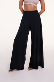 In a studio setting, Courtney wears the Sunday Pima Pant in Black, highlighting the elastic waistband and fluid, wide-leg silhouette. sizing: Courtney wears size Small