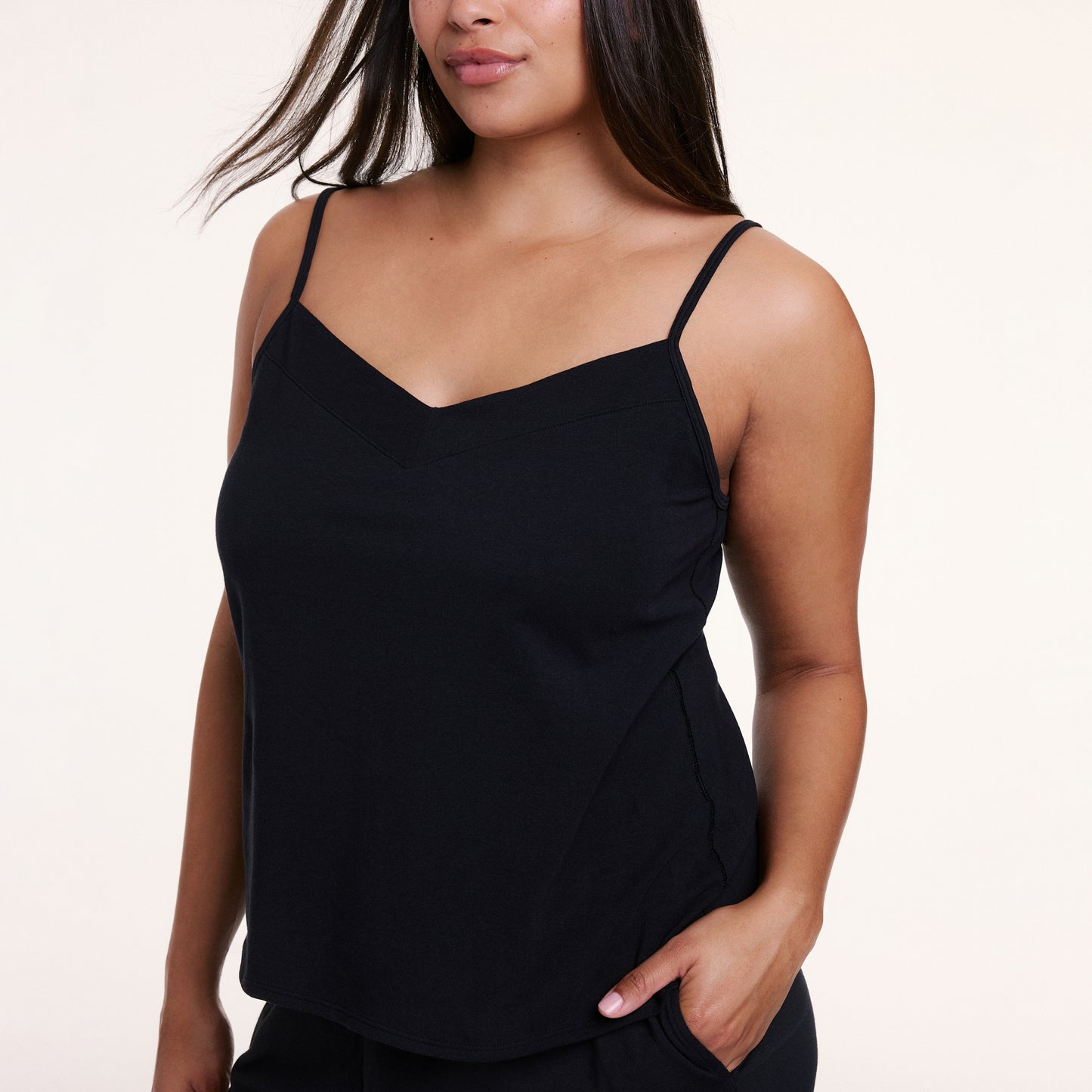 In a studio setting, Alana wears the Sunday Pima Tank in Black, highlighting the scoop neckline, thin straps, and smooth, drapey fabric.