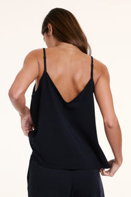 In a studio setting, Linni wears the Sunday Pima Tank in Black, showing the V back, adjustable straps, and relaxed silhouette.