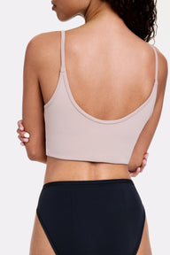 In a light gray studio, Courtney wears the Whipped Knit Scoop Bralette in Mushroom with black underwear, shown from the back highlighting thin adjustable straps and a smooth, wide band for comfortable support.