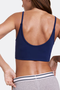 In a studio setting, Linni wears the Whipped Knit Scoop Bralette in Noir, shown from the back with a scoop back design and thin adjustable straps. The soft, stretchy fabric offers lightweight, wireless comfort with a smooth, longline fit.