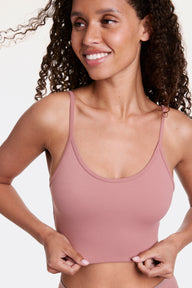 In a studio setting, Courtney wears the Whipped Knit Scoop Bralette in Plum, gently holding the hem to show the longline fit. The scoop neckline and thin adjustable straps pair with soft, stretchy fabric for lightweight, wireless comfort.