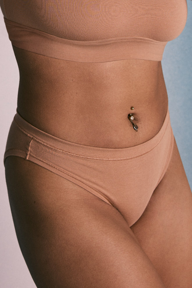 Close-up of a model's midsection, showcasing the Cloud Cotton Scoop Bralette and Cloud Cotton Bikini in Dune.