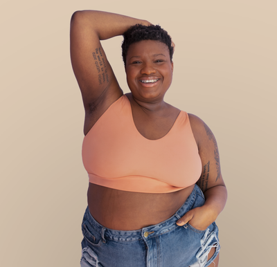 Woman wearing the Bliss Bralette in the color Blush with the word "worthy" embroidered on the side