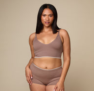 Woman wearing the Lounge Triangle Bralette in the color Oyster sizing: Alexandra wears size Large